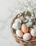 Nest of soft colored speckled Easter eggs lies among delicate blossoms and feathers