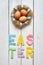 Nest wreath, eggs, easter folded paper origami colorful lettering on white wooden planks rustic background