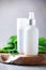 Nettle lotion, cream, shampoo or soap in white bottle and fresh nettles leaves on grey background. Medicinal herb for health and