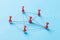 Network with red pins and string, An arrangement of colorful pins linked together with string on a blue background suggesting a