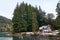 NEUQUEN, ARGENTINA - SEPTEMBER 8, 2015: Small rustic cabin surrounded by tall green pine trees next to the pier of Mansa Bay in
