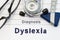 Neurological diagnosis of Dyslexia. Neurological hammer, stethoscope and doctors glasses lie on doctor workplace on sheet of noteb