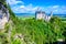 Neuschwanstein Castle in beautiful mountain scenery of Alps- in the background you can see the Lake Forggensee - near Fuessen,