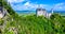 Neuschwanstein Castle in beautiful mountain scenery of Alps- in the background you can see the Lake Forggensee - near Fuessen,