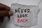 Never Look Back write on crunched paper isolated on wooden table
