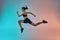 Never stop run Full length of young athlete woman with perfect body in sports clothing jumping in studio against