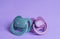 New baby pacifiers on purple background, closeup