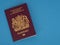 New Bergundy UK passport, no longer showing words `European Union`. On blue surface.