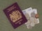 New Bergundy UK passport, no longer showing words `European Union`. With currency, pounds sterling. On cloth background.