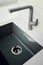A new black kitchen sink made of artificial stone and a faucet. The concept of modern kitchen interior. Vertical photography