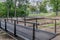 New black metal bridge over a stream, old bridge removed and temporarily placed on the lawn next to a footpath