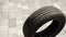 New black tire rolls alone on grey paved road closeup