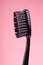 New black toothbrush isolated on pink background