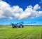 New blue tractor in field work with trailed sprayer, winter crop fertilizers, spring crop fertilizers