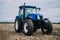 New blue tractor Holland in motion at demonstration field site at agro exhibition AgroExpo. Tractor working on the farm, modern
