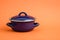 New And Clean Covered Dark Blue Saucepan on Orange Background