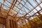 New construction home framing against blue sky, closeup of ceiling frame.