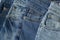 New denim pants clothes pile background. Stack of blue jeans different shadows