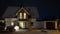 New detached house with a gable roof and garage surrounded by Christmas lighting and snow