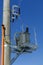 New distribution transformer on concrete power pole with external electric separator against the blue sky.