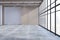 New empty concrete office premises interior with panoramic windows, city view, shadows and mock up place on wall.