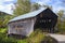 New England covered bridge spanning a river during autumn season