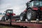 New farm tractors and trolleybus being shipped on rails. Special freight train carrying trolley-buses and agriculture tractors.