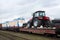 New farm tractors and trolleybus being shipped on rails. Special freight train carrying trolley-buses and agriculture tractors.