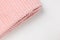 New folded pink throw fleece fabric with lines on white background, closeup