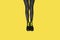 New gray female boots with bright yellow laces on straight, long slender woman legs in gray tiger print tights isolated on yellow