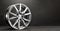 new grey alloy wheels on a dark textured black background. car wheel , copy space panorama empty space