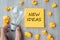 New Idea words on yellow note and crumbled paper with Businessman holding lightbulb on wooden table background. Creative,