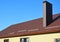 New installed brown metal tiled roof with plastic rain gutter system, snow board protection, chimney, house roofing construction