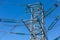 New large mast of an air power line close up, high voltage electricity pylon with thick wires and insulators, blue sky