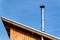 New metal chimney pipe on wooden house. Stainless steel chimney on house. Ecological wood heating. Environment. Lightning
