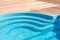 New modern fiberglass plastic swimming pool entrance step with clean fresh refreshing blue water on bright hot summer