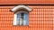 New, modern roof made of red ceramic tiles and a large attic window.