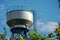 New modern water tower on the background of blue sky and forest. Methods of water storage for irrigation of agricultural crops in