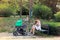 New mom on maternity leave with her baby outside for stroller walking, she is sitting on park bench and breastfeeding