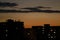 New moon rising behind city skyline with lit windows in the evening