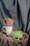 New mugs on a wooden stump, with a red flower, on a background of gray fabric and a wooden box. Still life. Photo of