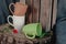 New mugs on a wooden stump, with a red flower, on a background of gray fabric and a wooden box. Still life. Photo of