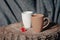 New mugs on a wooden stump, with a red flower, on a gray fabric background. Still life. photo utensils