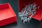 New nickel-plated screws in a red container. Accessories for mechanics on a wooden table