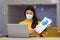 New normal of Asian woman in yellow shirt wearing surgical face mask meeting via VDO conference show sale report and explain in