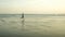 New normal beach running workout - wide lens view of young fit and attractive man jogging barefoot on sea wearing face mask