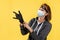 The new normal. A female robber in a protective mask and glasses, puts on gloves. Yellow background. The concept of crime