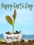 A new plant growing in rich soil inside a broken egg shell. Distant fields and blue sky are in the background.