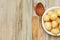 New Raw Potatoes in Bowl on Rustic Wooden table. Close up view, Wooden Spoons, over Wooden Background.