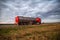 New red truck with a tanker truck transports gasoline against the background of the cloudy sky in the evening. Dangerous goods